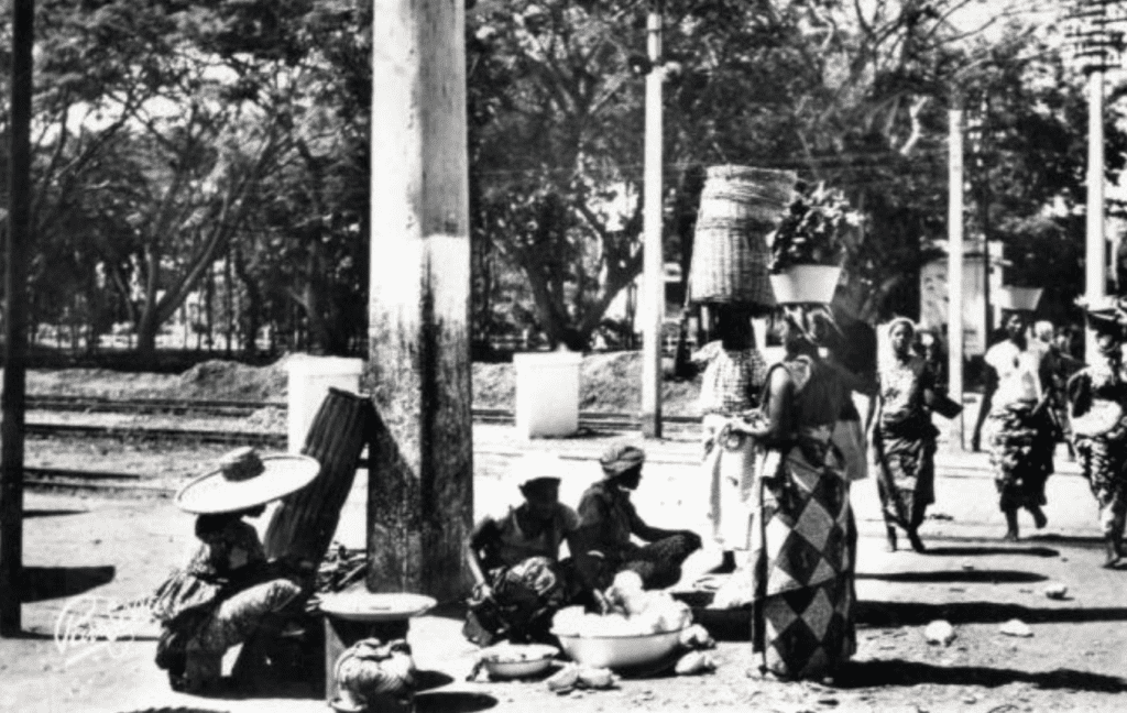 A Market scene with a few carrying merchandise on their heads